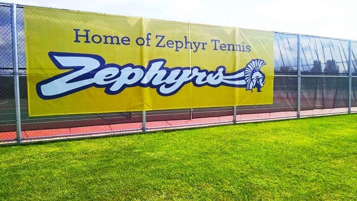 Outdoor mesh banner used for school sports facility branding. Durable mesh material allows airflow while providing clear, professional signage.